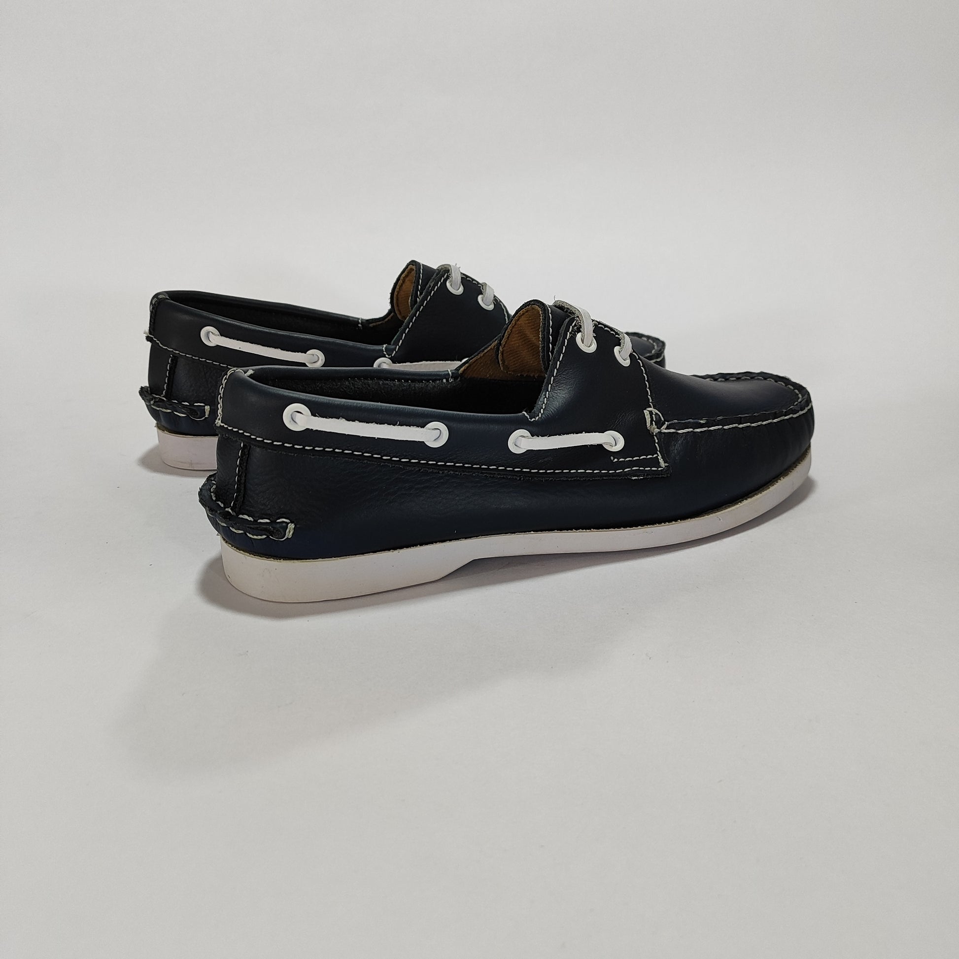 Par de náuticos de cuero azul con suela clara, vista lateral