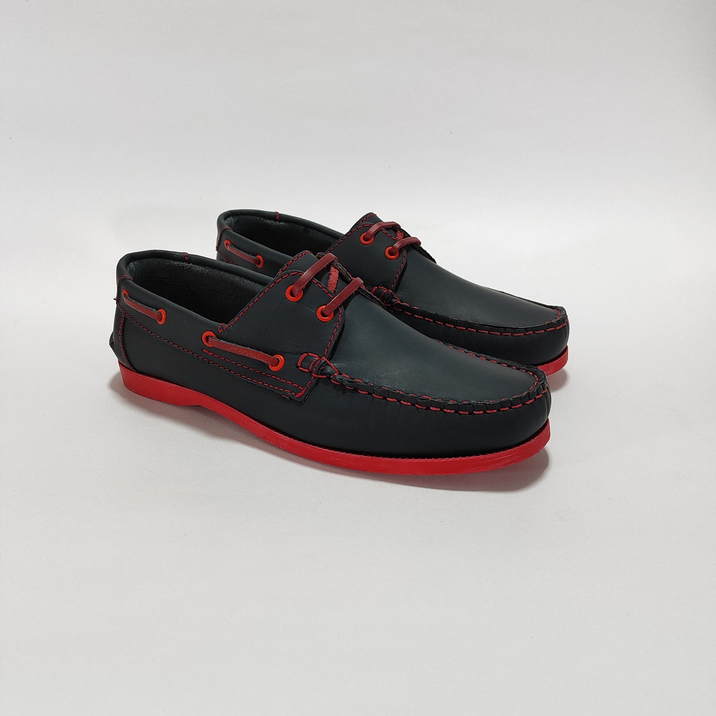 Apaches náuticos de cuero azul con suela y cordones rojos, vista tres cuartos